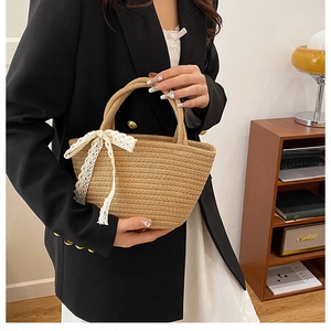 Detail of hand-woven straw tote bag with a white lace bow and sturdy round handles