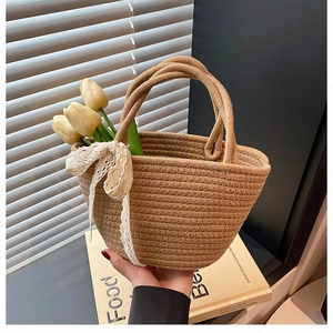 Detail of handmade straw beach bag with white lace bow and sturdy woven handles