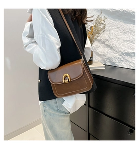 Close-up of vintage brown leather crossbody bag with elegant golden horseshoe buckle
