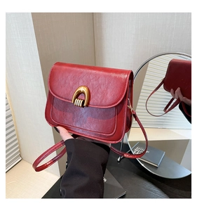 Detail showing red PU leather crossbody bag with vintage texture and gold U-shaped hardware