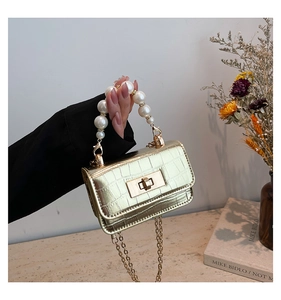 Détail du mini sac doré effet crocodile avec poignée en perles et bandoulière en chaîne
