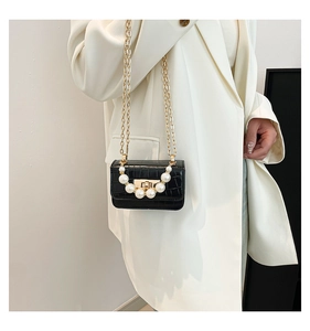 Détail du sac noir motif crocodile avec poignée de perles et bandoulière chaîne dorée