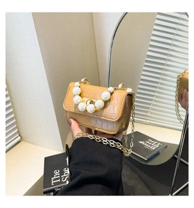 Detail of khaki croc-effect mini bag with pearl handle and golden chain strap