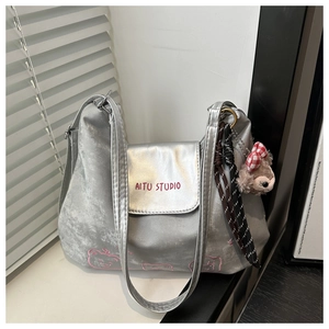 Detail der silbernen Metallic-Tasche mit rosa Stickerei und einem Plüschbären-Anhänger