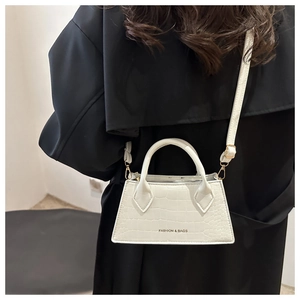 Close-up of white mini square bag with crocodile pattern and adjustable strap detail
