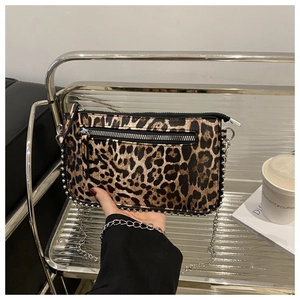 Detailed macro of leopard print handbag featuring silver studs and metal chain strap