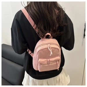 Detailansicht des rosa Cord-Mini-Rucksacks mit Doppelreißverschlüssen und Trägern