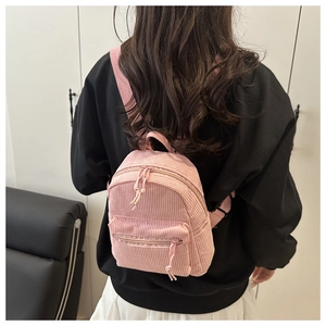 Rückansicht eines Models mit einem rosa Cord Mini-Rucksack und silbernen Reißverschlüssen