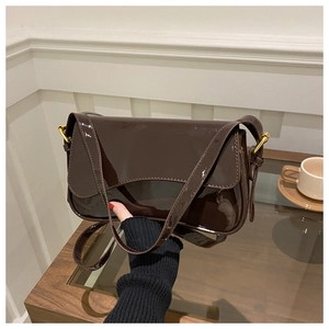 Detailed view of dark brown patent leather shoulder bag with polished gold hardware buckles