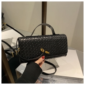 Detail of black woven leather handbag showing gold knot buckle and fine texture
