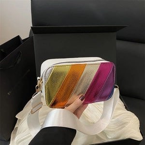 Chic camera bag with colorful metallic stripes and wide nylon strap held by a person