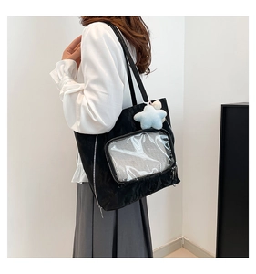 Detail of black tote bag with clear window pocket and blue star plush charm accessory