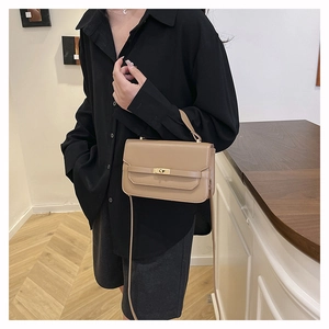 Détail du sac à main kaki avec fermoir rotatif doré et poignée élégante porté par un mannequin