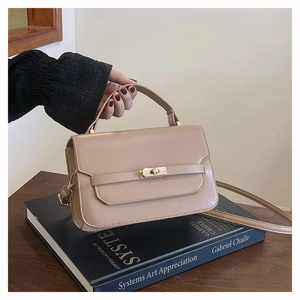 Gros plan du sac à main beige en cuir avec fermoir doré rotatif et poignée élégante