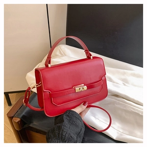 Détail d'un sac à main rouge en similicuir avec fermoir rotatif et bandoulière réglable