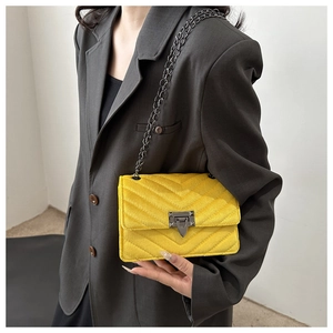 Detail der gelben Crossbody-Tasche mit Chevron-Steppung, Metalldrehverschluss und Kette