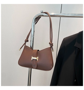Détail d'un sac sous les aisselles en cuir marron avec une boucle en métal doré en forme d'H