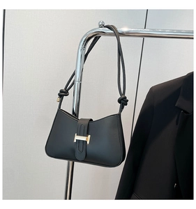 Gros plan d'un sac demi-lune en cuir noir avec un fermoir en H doré élégant