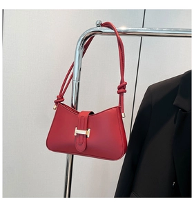 Détail du sac d'épaule en cuir rouge avec ferrures dorées et finitions de bandoulière