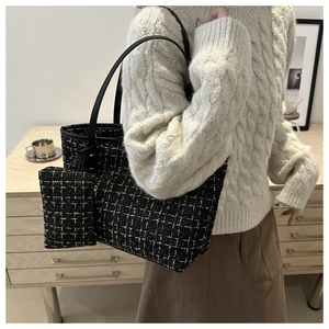 Dettaglio della borsa tote in tweed con pochette coordinata e manico in pelle nera sul modello