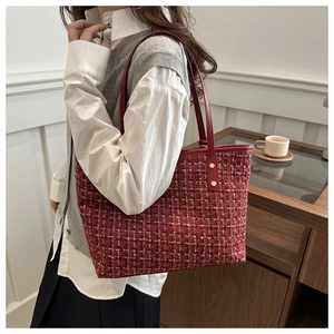 Detail of red and gold tweed tote bag with leather straps on model in elegant interior