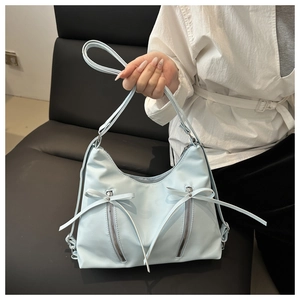 Detailansicht der hellblauen Hobo-Tasche mit dekorativen Schleifen und vertikalen Zippern