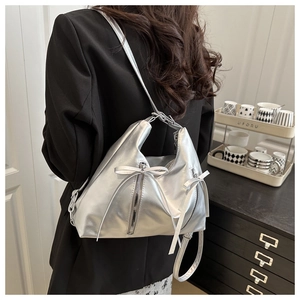 Detailansicht der silbernen Metallic-Tasche mit Schleife und seitlichen Reißverschlüssen