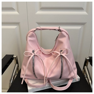 Detail der rosa Schleifenhandtasche mit Silberreißverschlüssen auf Ledersessel