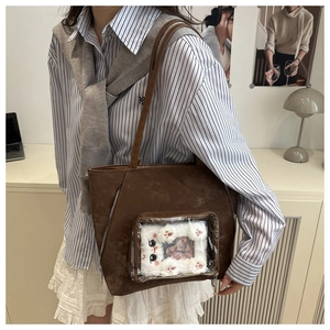 Detailed view of brown ita bag with transparent PVC window and plush cat accessory