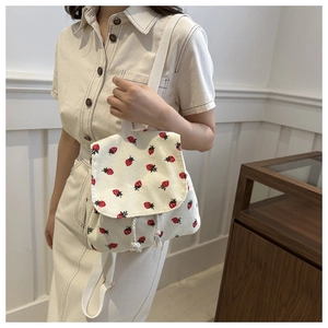 Close-up of beige corduroy backpack featuring red strawberry patterns and drawstring detail