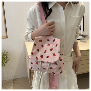 Detailed texture of pink corduroy backpack featuring red strawberry patterns and drawstring
