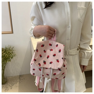 Detailed texture of pink corduroy fabric with red strawberry print on this cute backpack