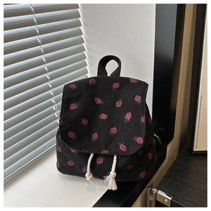 Detail of black corduroy mini backpack with red strawberry prints and tassel drawstrings