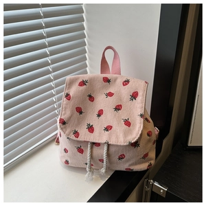 Detail of pink corduroy backpack featuring red strawberry patterns and cotton drawstring