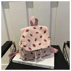 Detailed close-up of pink corduroy backpack featuring red strawberry prints and drawstring