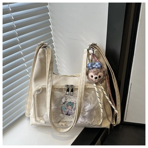Close-up of cream white ita bag featuring a clear window and plush charm detail