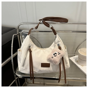 Detail view of off-white hobo bag with pleated texture and stylish plush cloud charm
