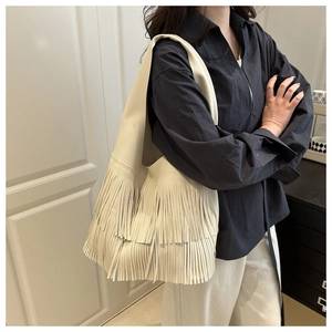 Detail view of the layered fringe tassels and lychee grain leather on large hobo bag