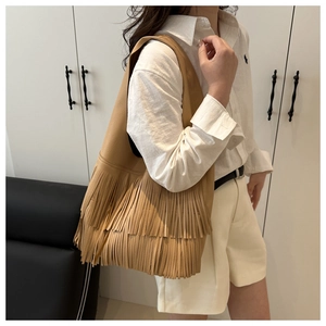 Detail of khaki fringed tote bag showing long tassels and litchi grain faux leather texture