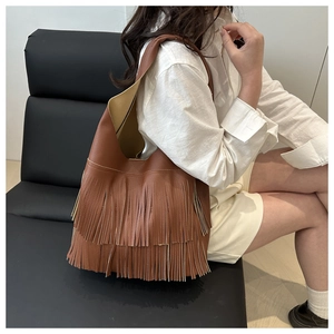 Close-up of brown litchi grain leather shoulder bag featuring long tiered tassels