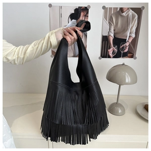 Close-up of black fringe tote bag featuring textured lychee pattern and long leather tassels