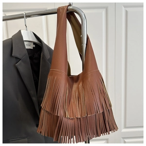 Detailed close-up of brown leather shoulder bag with stylish fringe and litchi grain texture