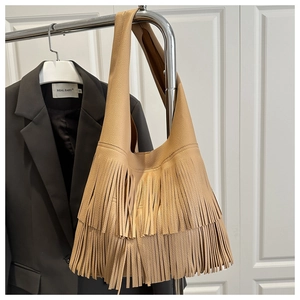 Close-up of khaki pebbled leather shoulder bag with long bohemian tassels on display