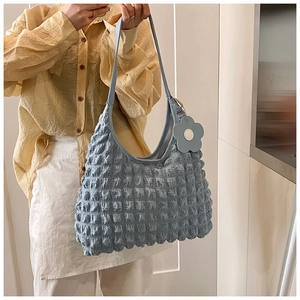 Gros plan sur un sac cabas bleu à texture gaufrée avec un pendentif fleur bleu clair