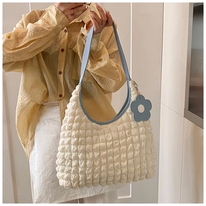 Détail du tissu plissé blanc et de la bandoulière bleu clair avec pendentif en fleur