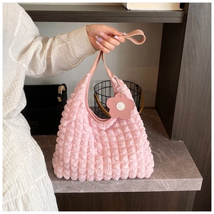 Dettaglio borsa rosa con trama a bolle, manici in pelle e ciondolo a forma di fiore