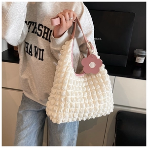 Détail du sac blanc gaufré avec bandoulière en cuir rose et breloque fleurie