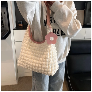 Détail du sac cabas gaufré blanc avec breloque fleur rose et bandoulière élégante