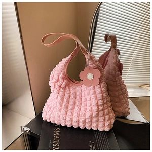 Détail du sac à bandoulière rose en tissu gaufré avec breloque fleurie et poignée
