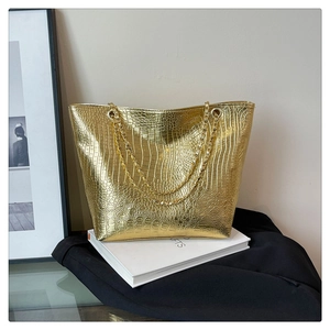 Close-up of golden crocodile pattern tote bag with decorative metal chain handles